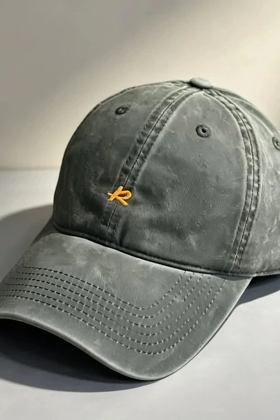 An olive washed baseball cap with a small embroidered motif on the front panel