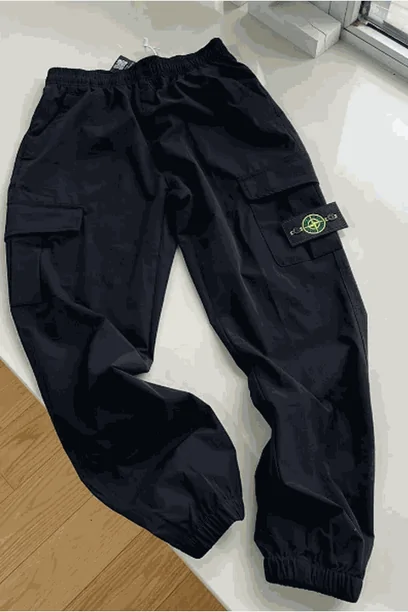 Black cargo-style trousers laid flat on a wooden floor